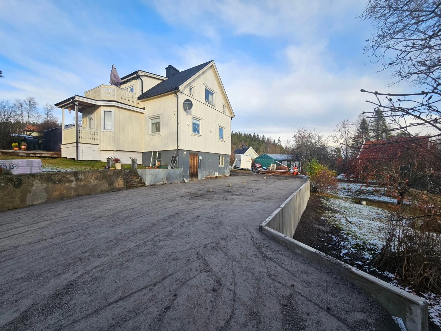 Breddad parkering med ny stödmur framför ett hus